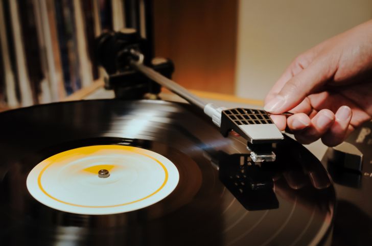 A woman with her hand on the record player
