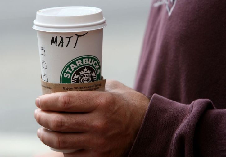 A Starbucks customer holds a coffee cup with their name written on the side