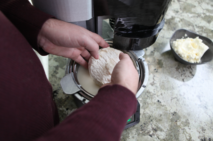 Pulling cheese out of cheese-making machine.