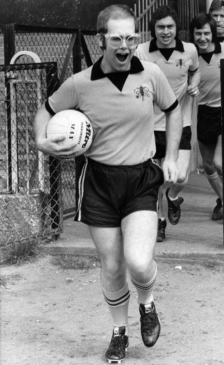 Pop singer and football club chairman Elton John leads Watford Football Club team out onto the pitch in 1974.