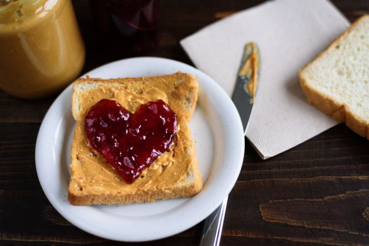 A piece of bread spread with peanut butter and jelly in a heart shape