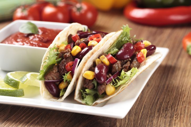 Two soft tacos on a plate with salsa