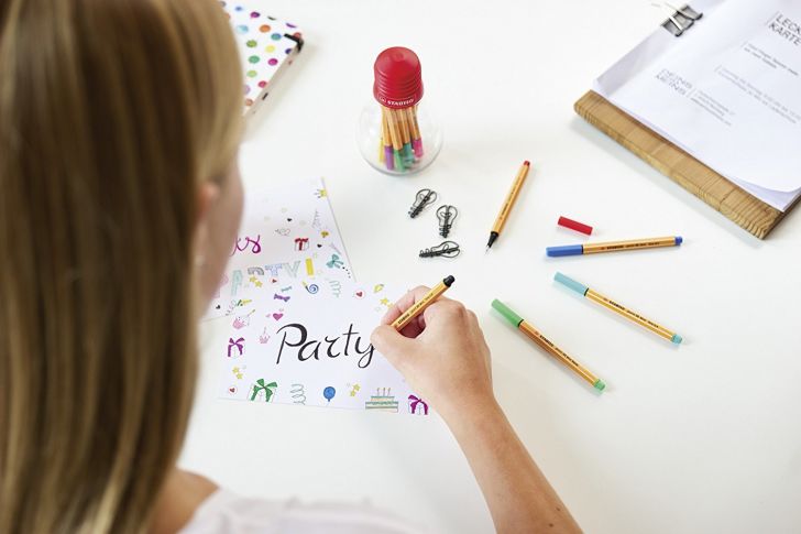 A woman writes 'Party' on with Stabilo Fineliner pens