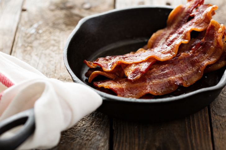 Sizzling hot bacon cooking in a cast iron skillet