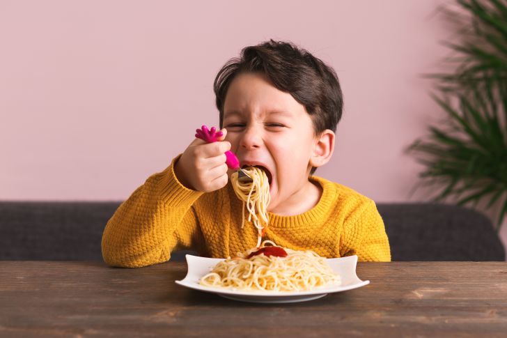 Young boy eats a plate of spaghetti