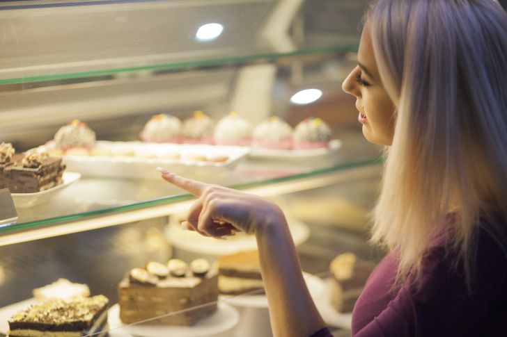 Woman picks out a dessert in a bakery