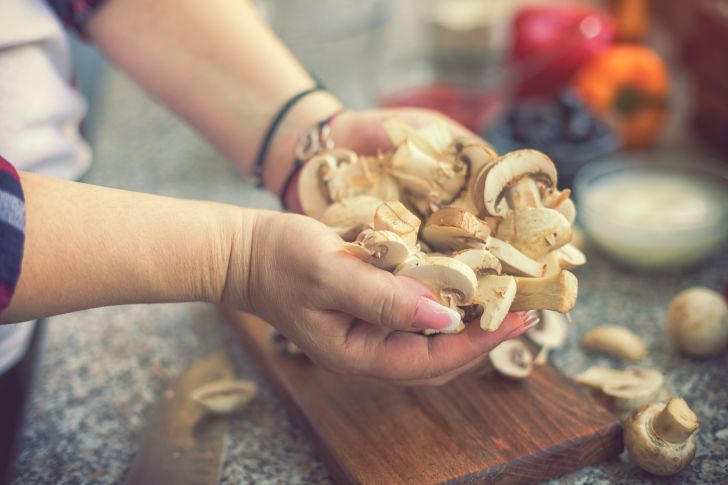 Woman preparing a mushroom pizza at home