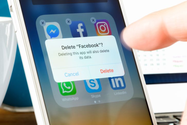 A finger deleting the Facebook app from a smartphone