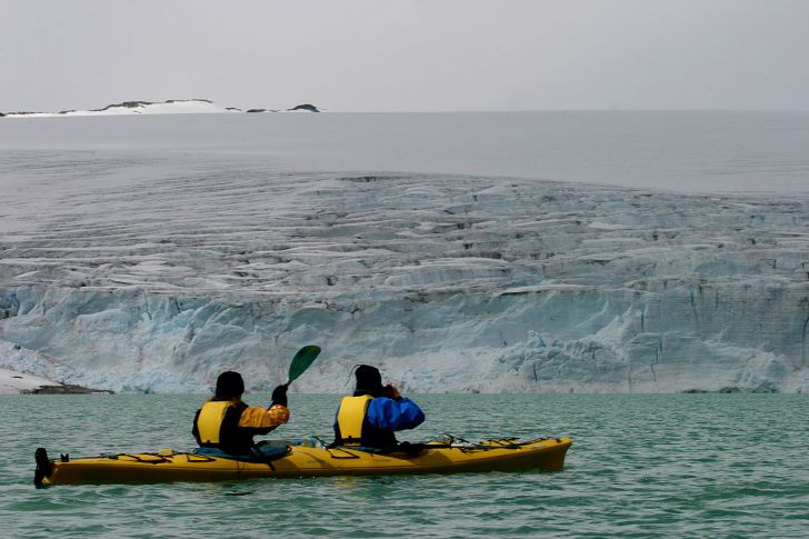 Two people kayak near glaciers