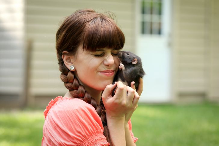 A woman plays with her pet rat