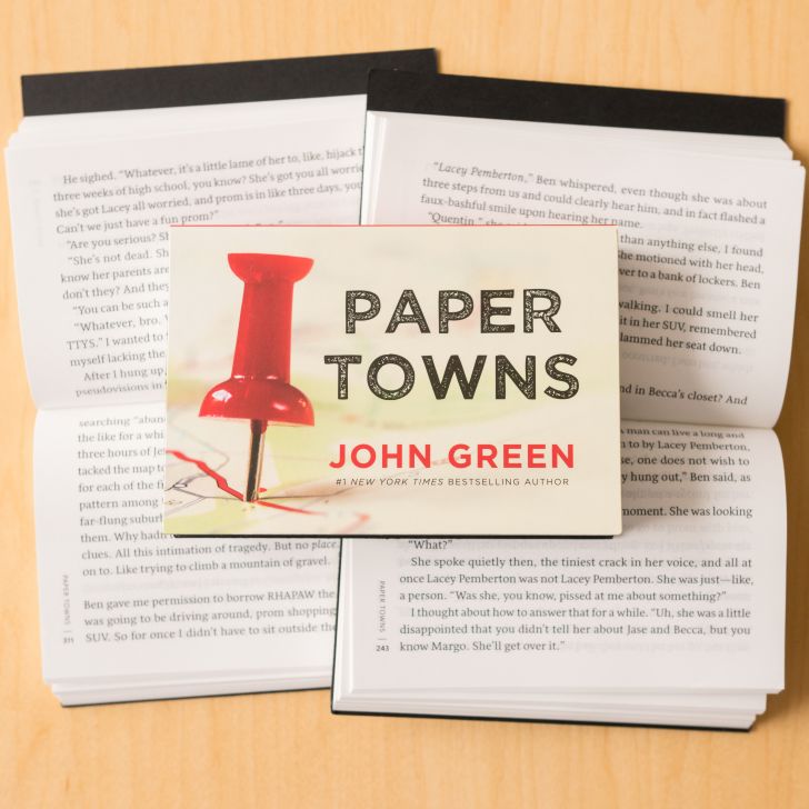A copy of the Penguin Mini version of 'Paper Towns' resting on two open copies of the book