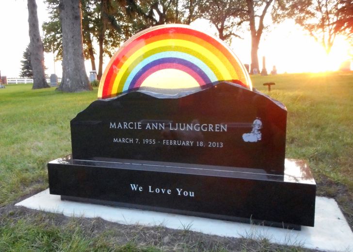 A headstone designed with a rainbow on top of it that reads 'Marcie Ann Ljunggren'