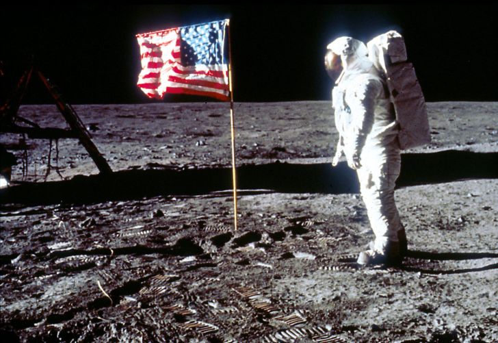 Buzz Aldrin poses next to an American flag on the surface of the Moon.