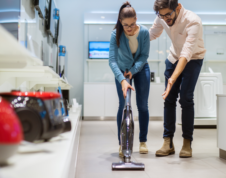 A woman tries out a stick vacuum at a store