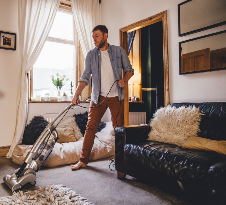 A man uses an upright vacuum