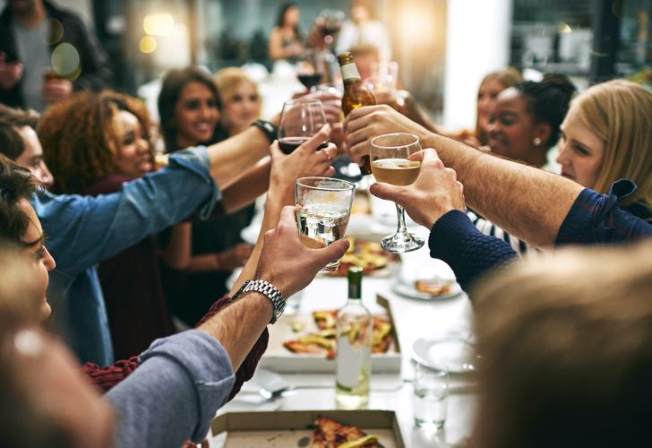A group of friends clinking glasses over a meal