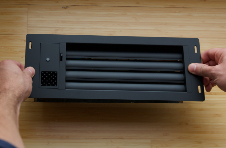 A black vent sits on the floor before installation.