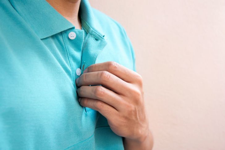 A man buttons his shirt