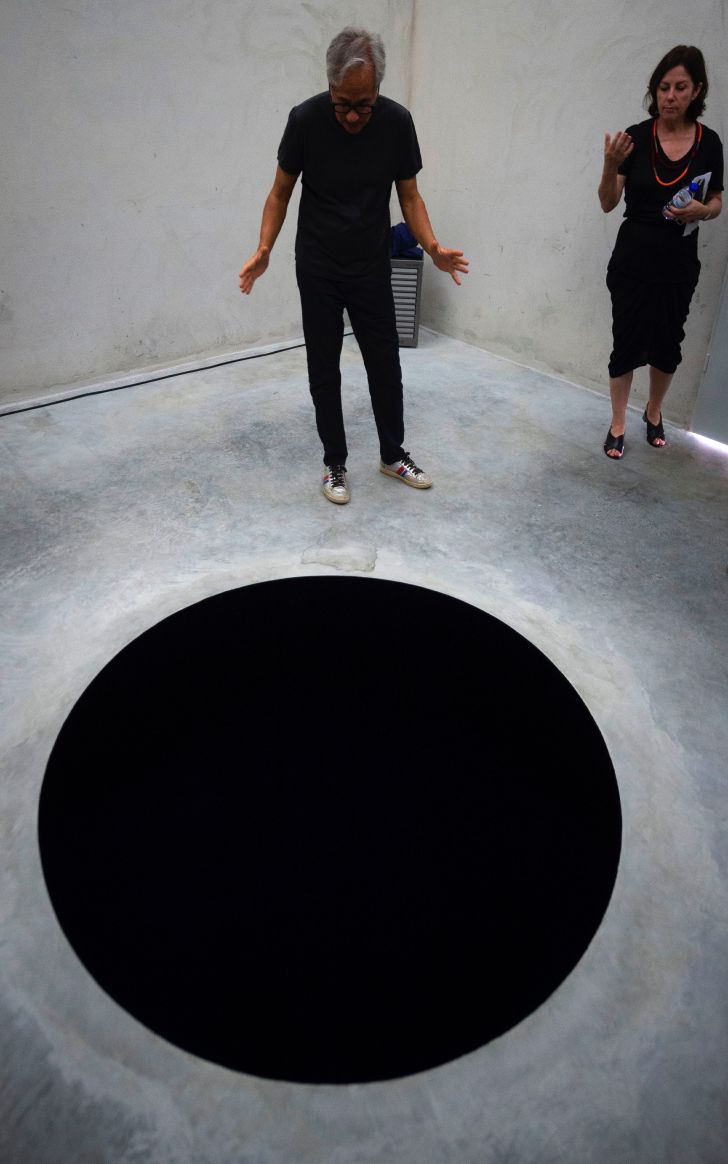 British contemporary artist Anish Kapoor (L) and and curator Suzanne Cotter stand next to his artwork 'Descent into limbo' during the opening of his exhibition entitled 'Works, thoughts, experiments' at the Serralves Foundation in Porto, on July 6, 2018
