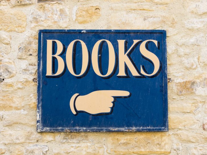 A blue sign with white letters spelling out the word "books" and a hand pointing
