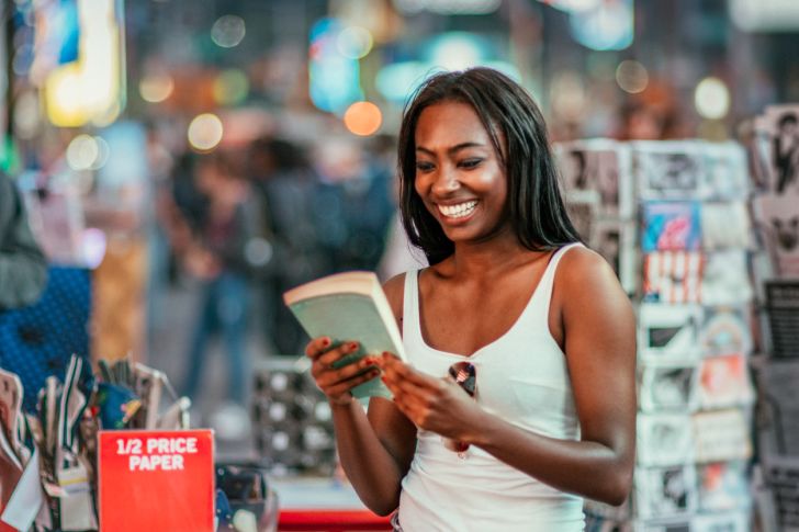 A woman browsing near a sign for half-price paperbacks at a bookstore