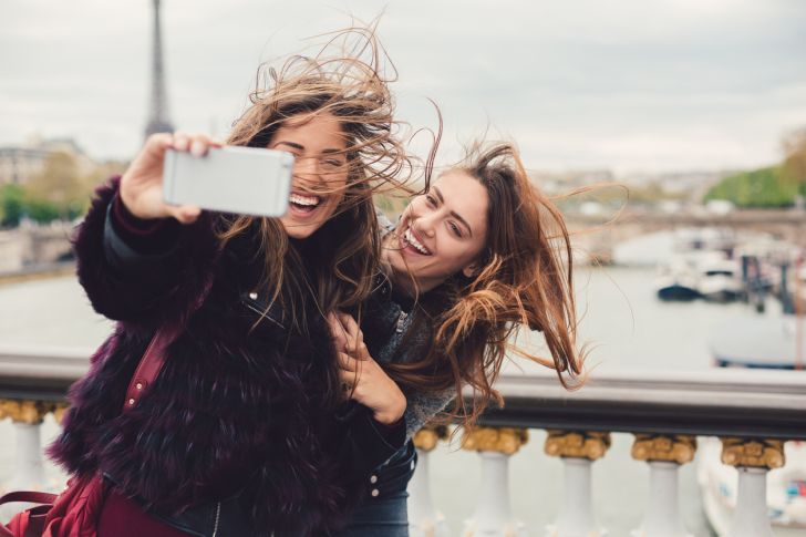 girls talking selfie in paris as wind whips their hair around