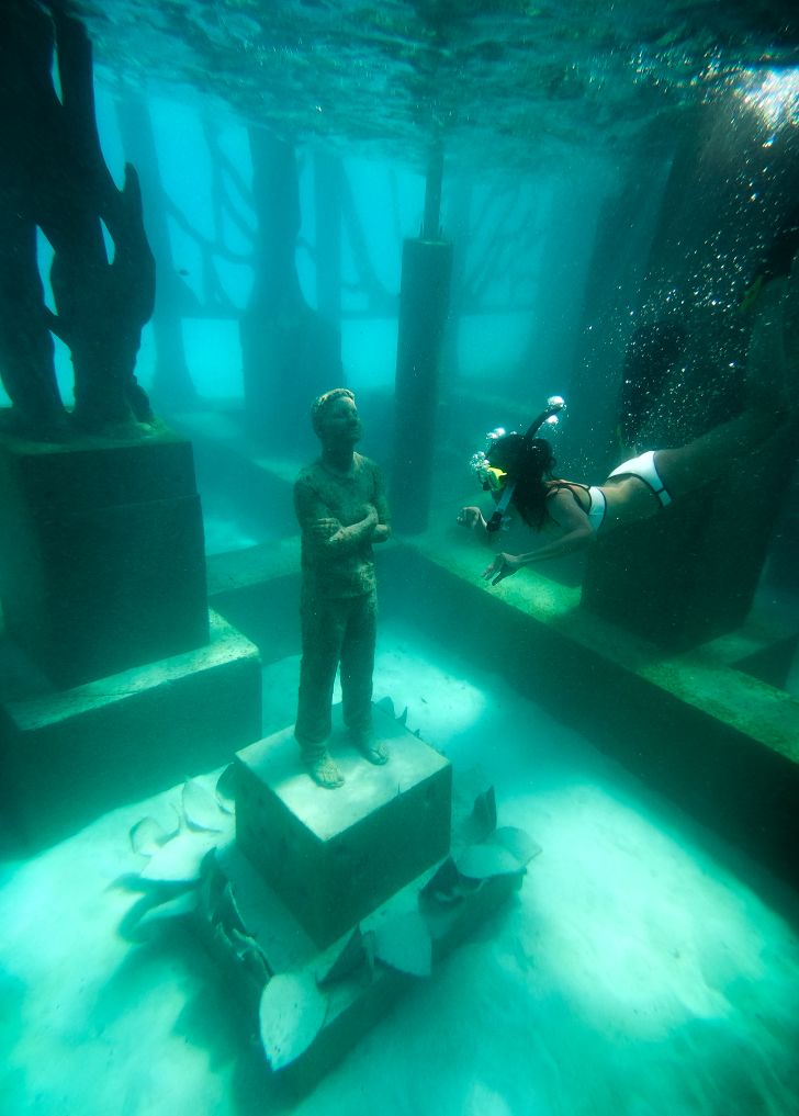 A snorkeler looks at a submerged sculpture