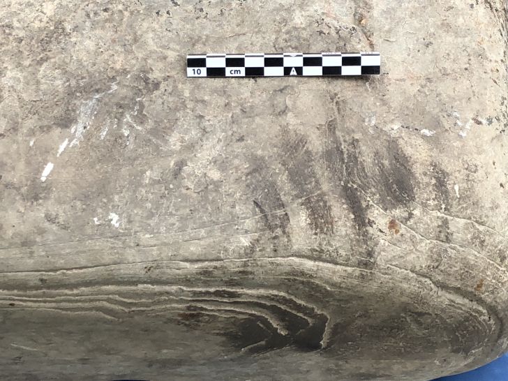 A close up of a dark handprint on a stone slab