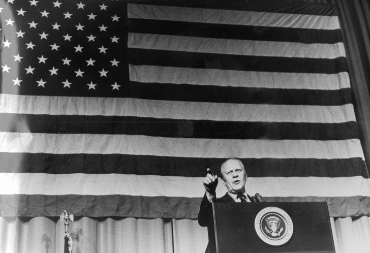 image of President Gerald Ford standing in front of an American flag and pointing toward an audience