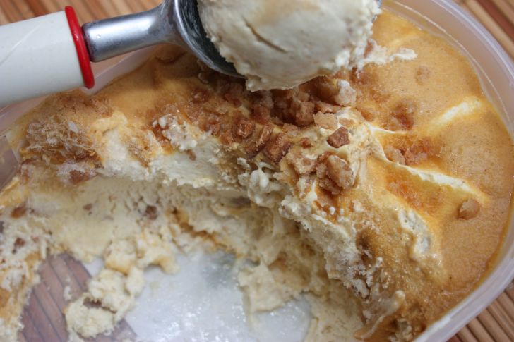 image of someone scooping from a vat of praline dessert