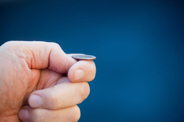 image of a hand flipping a coin