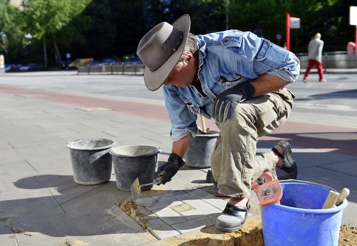 Demnig lays a Stolpersteine.