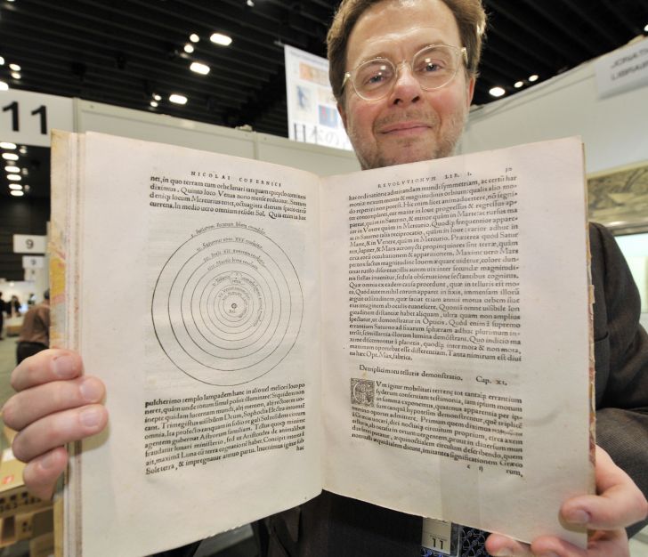 An antique bookseller displays a rare first edition of Nicolaus Copernicus' revolutionary book on the planet system.
