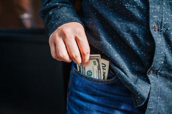 A male hand taking dollar bills out of a pocket