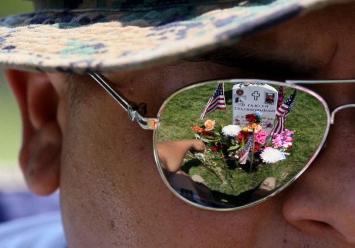 Ricky Parada sits at the grave of his little brother Cpl. Nicolas D. Paradarodriguez who was killed in Afghanistan, at Section 60 on Memorial Day at Arlington National Cemetery on May 28, 2012 in Arlington, Virginia