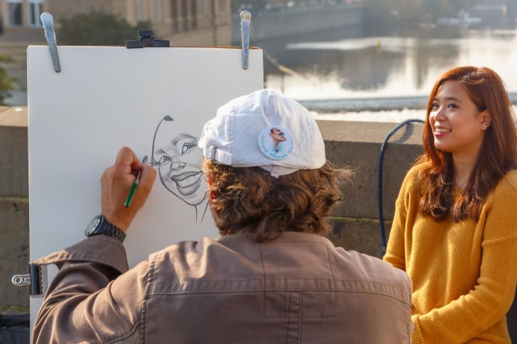 A street artist paints a caricature of a girl in Prague