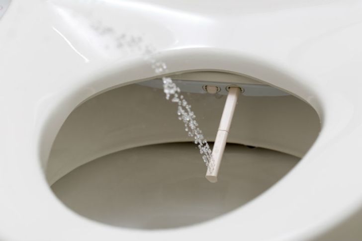 A bidet sprays water out of a toilet