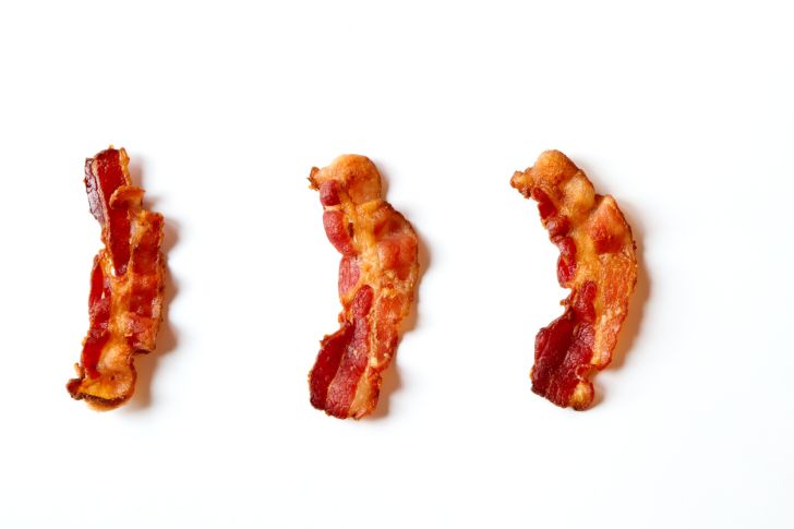 Three strips of bacon on a white background