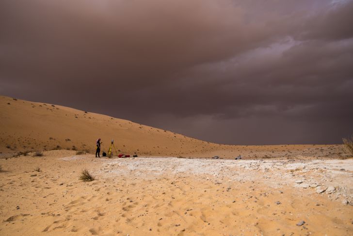 A surveyor stands in the desert.