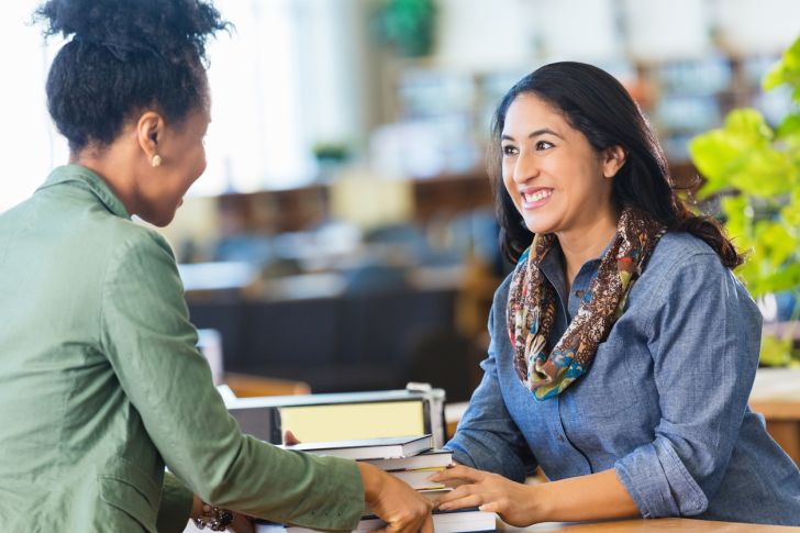 A friendly librarian helping a patron at a desk