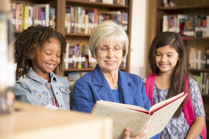 A senior librarian reading to small children