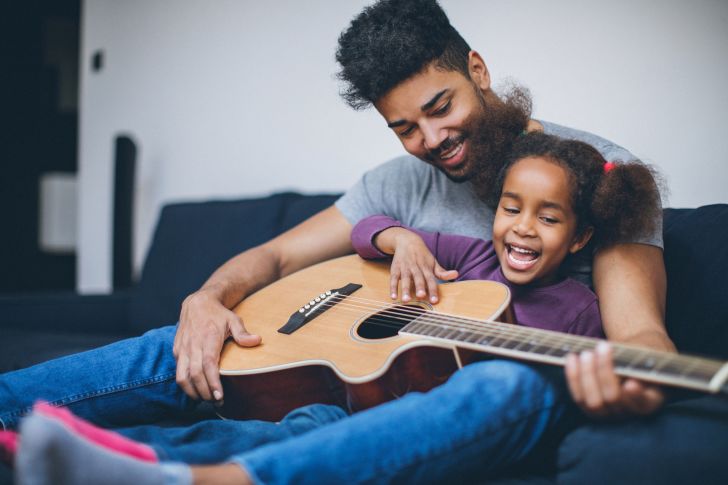 Man and daughter playing guitar