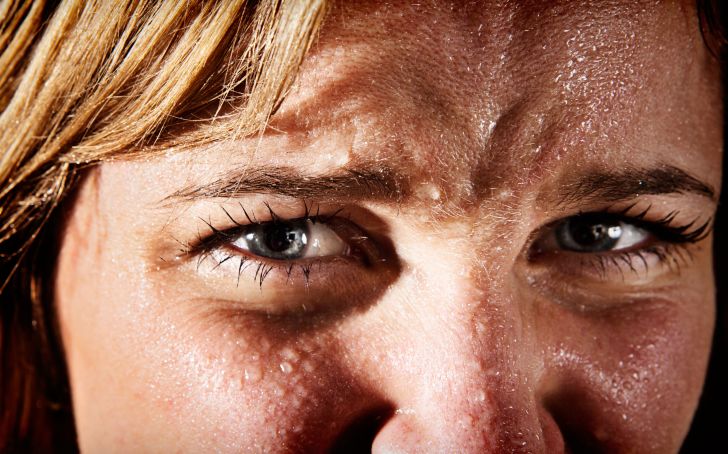 Close-up of perspiring, tense, frowning young blonde woman