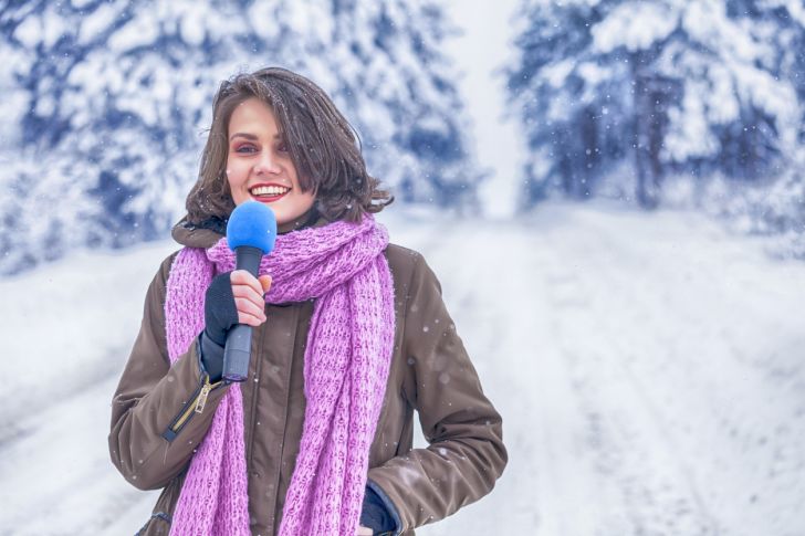 A young TV weatherperson in a snowy scene