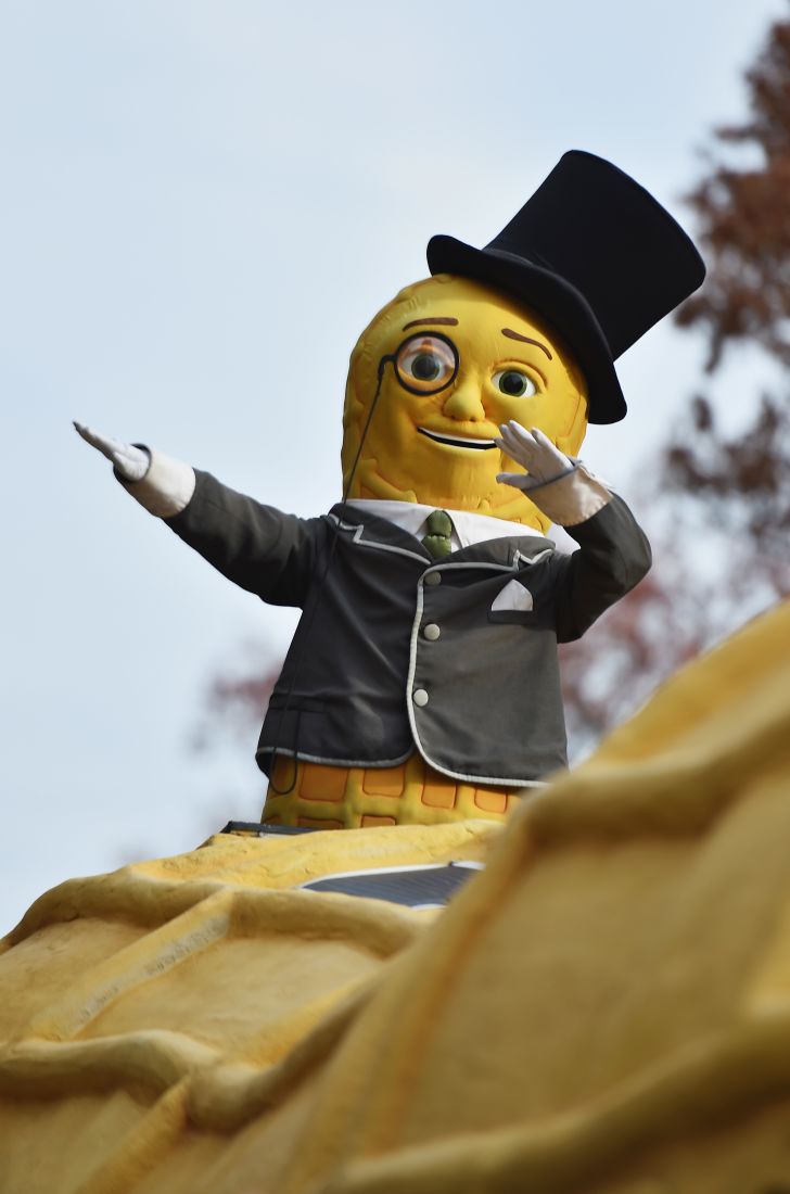 A large peanut wearing a suit and monocle is dabbing.