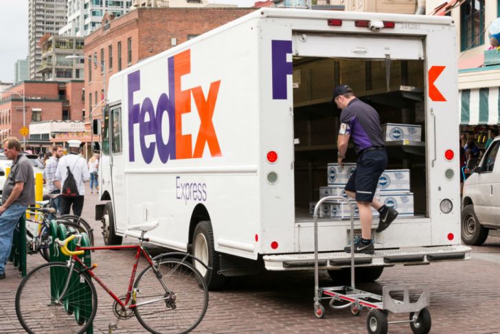 A FedEx driver examines the back of his truck