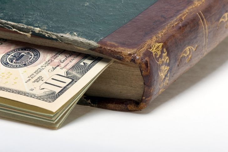 A stack of bills inside an older book A stack of bills inside an older book
