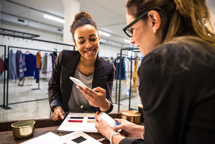 Two women looking at books of samples in a clothing store