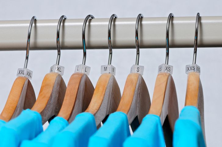 Turquoise women's t-shirts of various sizes from small to large hanging on wooden hangers