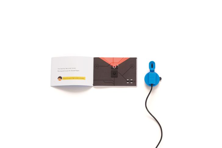 A blue Kano booklet of instructions sits next to a small blue sensor that looks like a periscope.